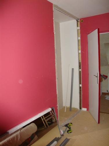 Voila ce que ça donne côté "petite" chambre. Avant la pose des portes. Seul hic, le placard se trouve derrière a porte d'entrée, mais l'espace exigu imposait cette réalisation.